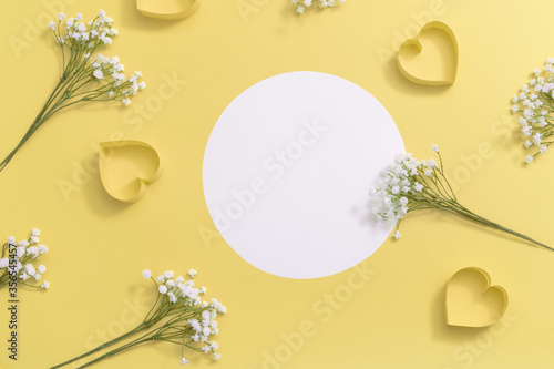 Top view of round white frame with paper hearts and gypsophila's flowers on yellow bright background , minimalistic beauty mock up. photo