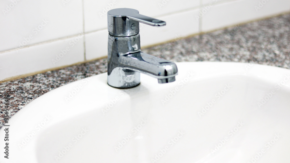 The Silver Faucet with white ceramic sink in the bathroom, using for cleaning and washing hands, hygiene health care for protecting corona virus. Remove and kill bacteria fungal by keeping sanitation. The Silver Faucet with white ceramic sink in the bathroom, using for cleaning and washing hands, hygiene health care for protecting corona virus. Remove and kill bacteria fungal by keeping sanitation.
