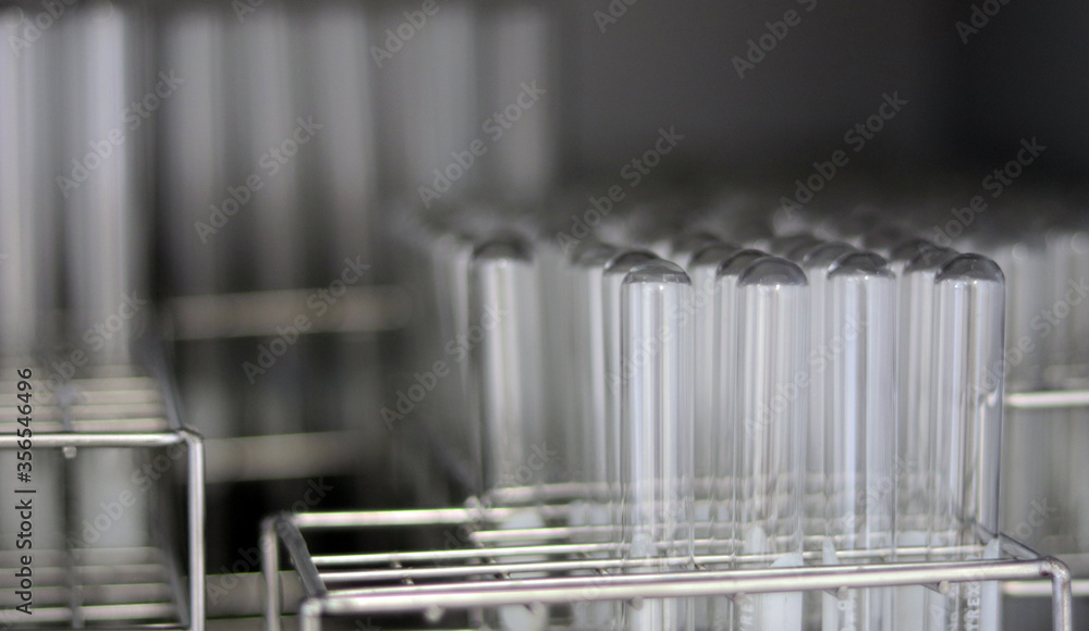 Transparent clear test tubes on racks, clean glasswares on the laboratory shelf for measuring solution or solvent in science experiment, chemistry equipment tools for analysis sample. Selective focus. Transparent clear test tubes on racks, clean glasswares on the laboratory shelf for measuring solution or solvent in science experiment, chemistry equipment tools for analysis sample. Selective focus.