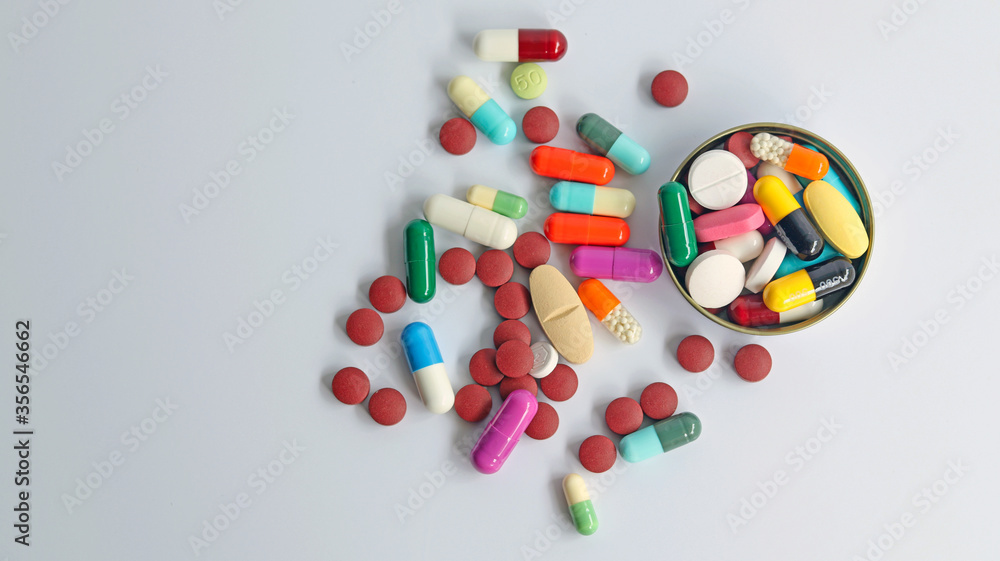 Top view of Medicines in bottle cover cap, colorful pills, tablets and capsules isolated in white background. Drug prescription use for medication in medical clinic, pharmacy pharmaceutical service.