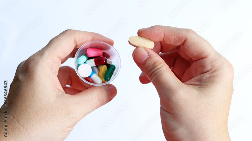 Patient woman holds medicine cup and a tablet of vitamin C in hands, ready to take medicines colorful pills, tablets and capsules for treatment the disease, prescription medication dosage from doctor. Patient woman holds medicine cup and a tablet of vitamin C in hands, ready to take medicines colorful pills, tablets and capsules for treatment the disease, prescription medication dosage from doctor.