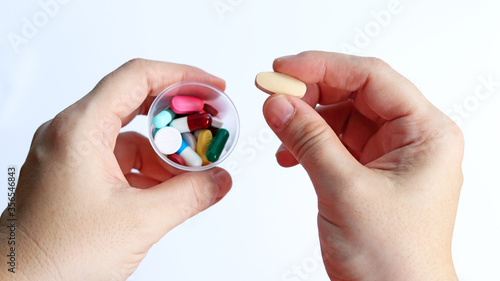 Patient woman holds medicine cup and a tablet of vitamin C in hands, ready to take medicines colorful pills, tablets and capsules for treatment the disease, prescription medication dosage from doctor.