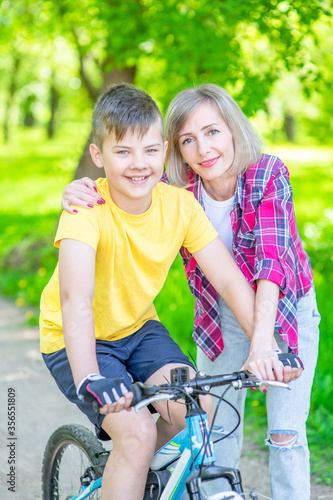 Sporty family leisure. Happy mother embraces her young son, who ride bikes in a summer park