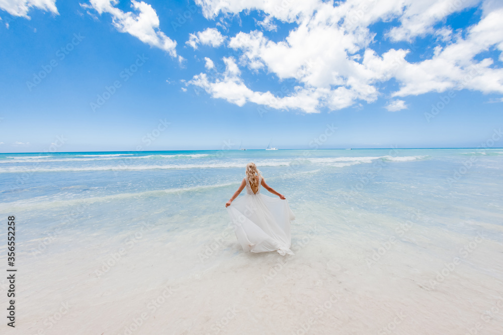 Bride back view in a white wedding dress walking on the sandy caribbean beach landscape on sunny day in Dominican republic Bride back view in a white wedding dress walking on the sandy caribbean beach landscape on sunny day in Dominican republic