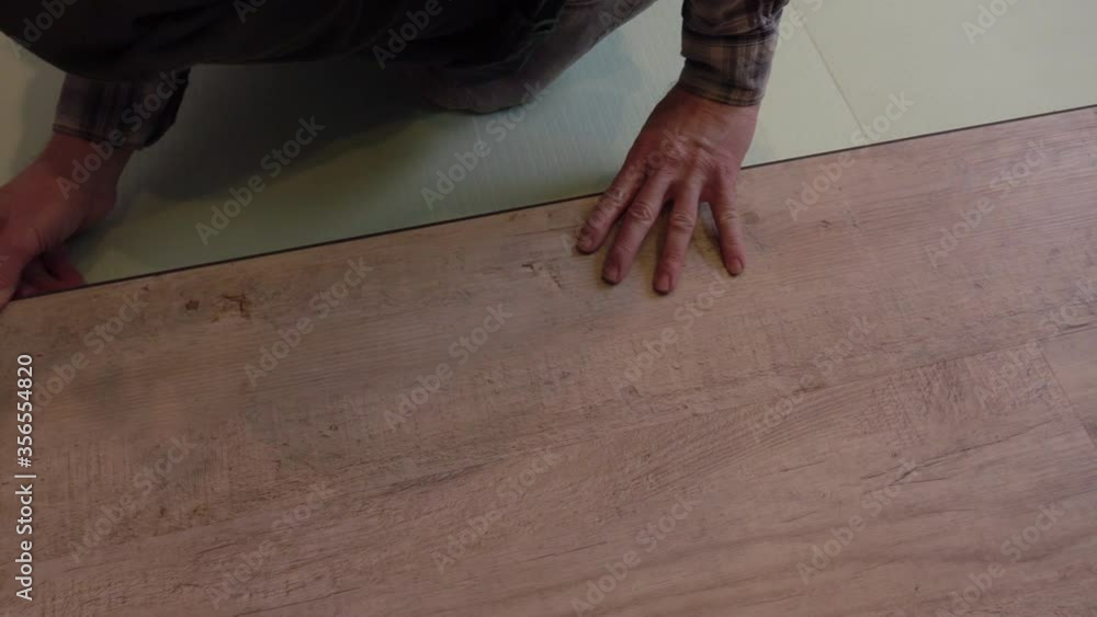 A worker puts a new laminate on the floor. Laying the floor covering. Master in the house. A worker puts a new laminate on the floor. Laying the floor covering. Master in the house.