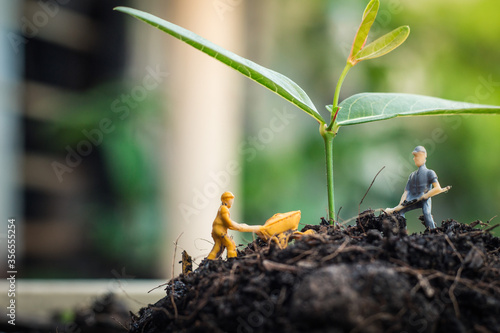 Miniature people team works to inspect and plant trees for a green world project. (We plant trees for a better world)