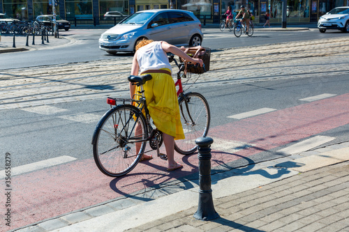Girl on a bicycle untangles her skirt