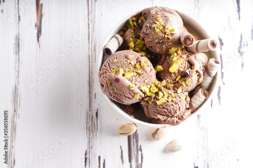 Chocolate ice cream balls with pistachio and cookies in a white bowl photo