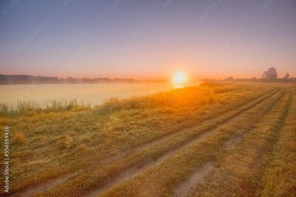 Morning landscape in fog dawn sun rural road early morning in summer.