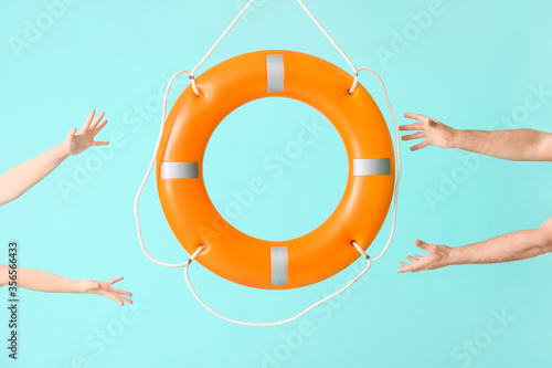 Human hands with lifebuoy on color background