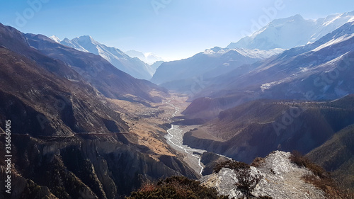 Early morning in Manang Valley, Annapurna Circus Trek, Himalayas, Nepal, with the view on Annapurna Chain and Gangapurna. Dry and desolated landscape. High, snow capped mountain peaks. Small torrent