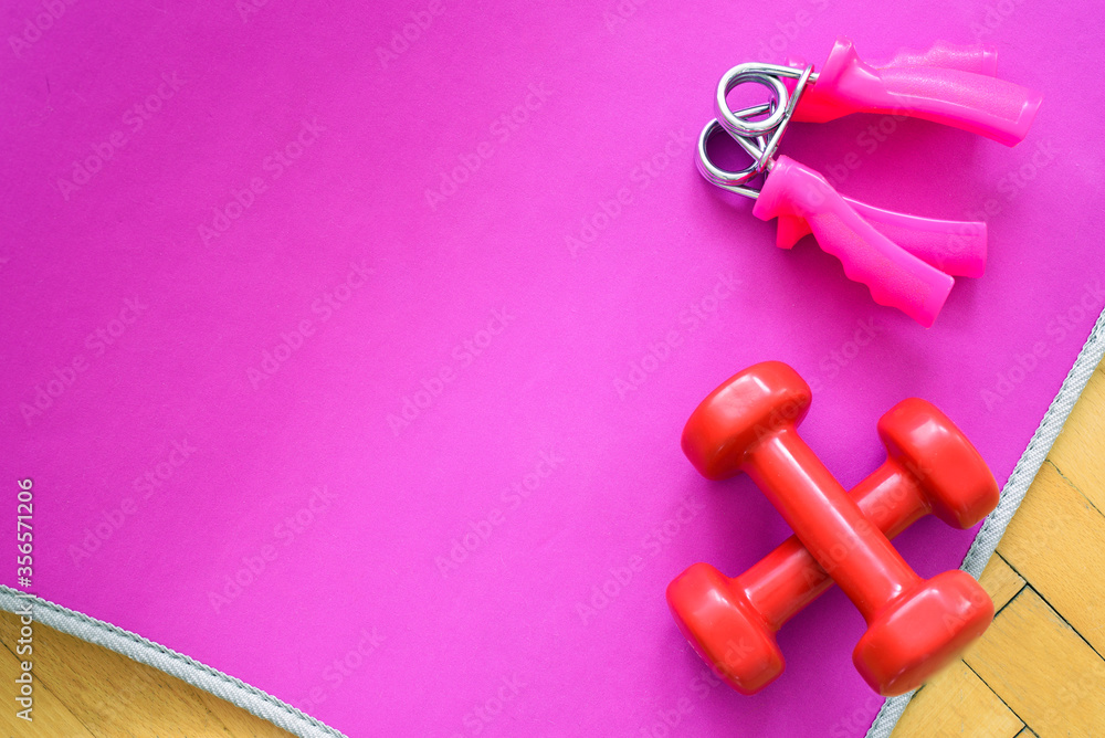 Top view of fitness equipment - pink mat for workout, two red dumbbells. Concept of training. Copy space. Top view of fitness equipment - pink mat for workout, two red dumbbells. Concept of training. Copy space.