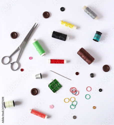 scissors, threads, needles and buttons on a white background