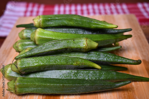 fresh lady fingers or okra vegetables on wooden chopping board