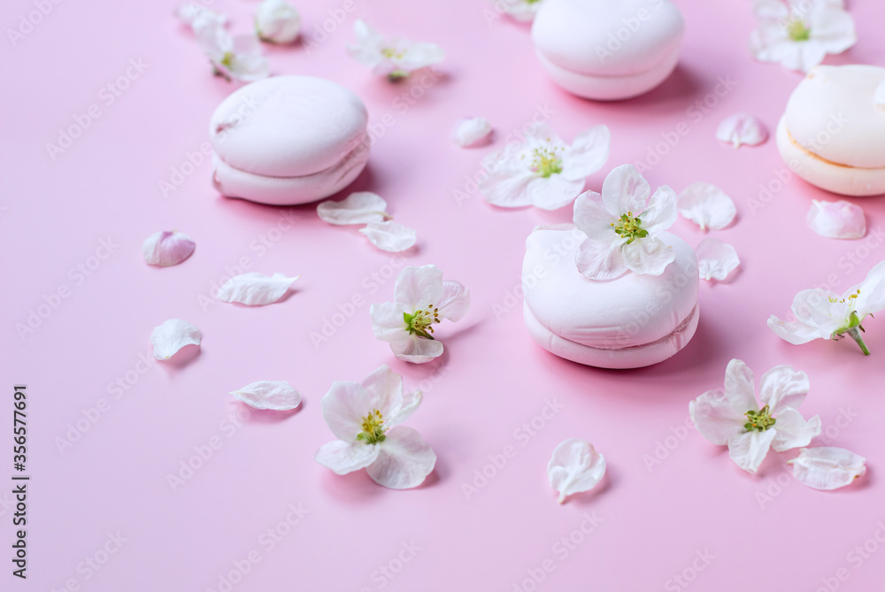 Pink marshmallows and flowers on a pink pastel background. Close-up.
