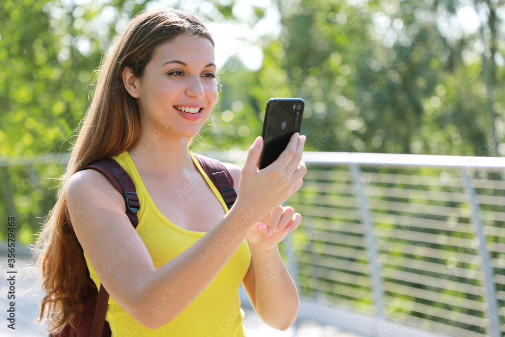 Portrait of smiling female hiker checking GPS coordinates with her smart phone looking for the right direction. Adventure, active lifestyle and eco tourism. Portrait of smiling female hiker checking GPS coordinates with her smart phone looking for the right direction. Adventure, active lifestyle and eco tourism.