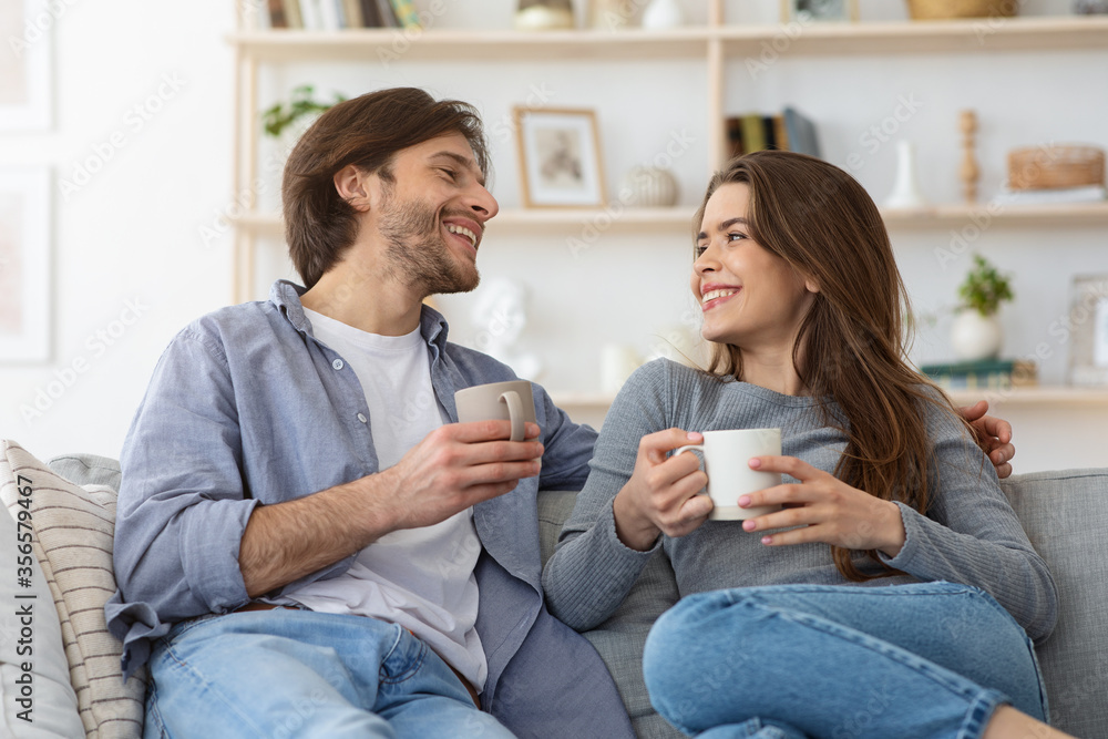 Cheerful couple having conversation and drinking coffee at home Cheerful couple having conversation and drinking coffee at home