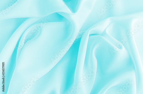 Satin silk fabric blue color for the background. Crumpled wavy silk. Texture of satin fabric