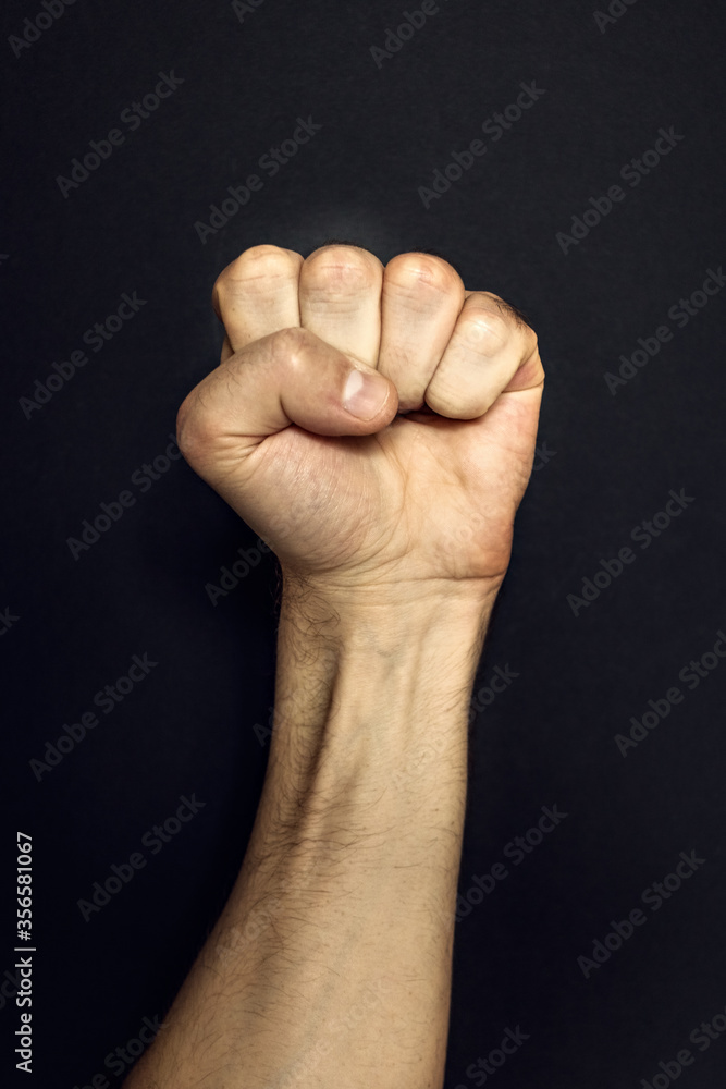 Male fist on a black background. Aggressiveness, masculinity, the concept of challenge Male fist on a black background. Aggressiveness, masculinity, the concept of challenge