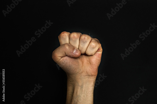 Male fist on a black background. Aggressiveness, masculinity, the concept of challenge