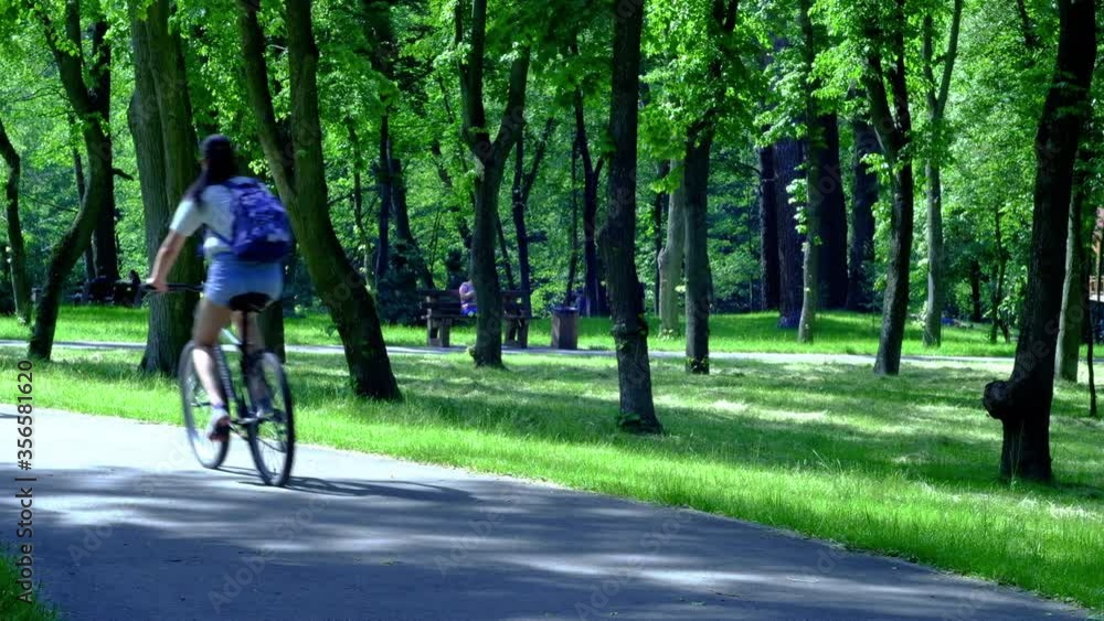 Girls ride a bike along the alley in the summer in the park Girls ride a bike along the alley in the summer in the park