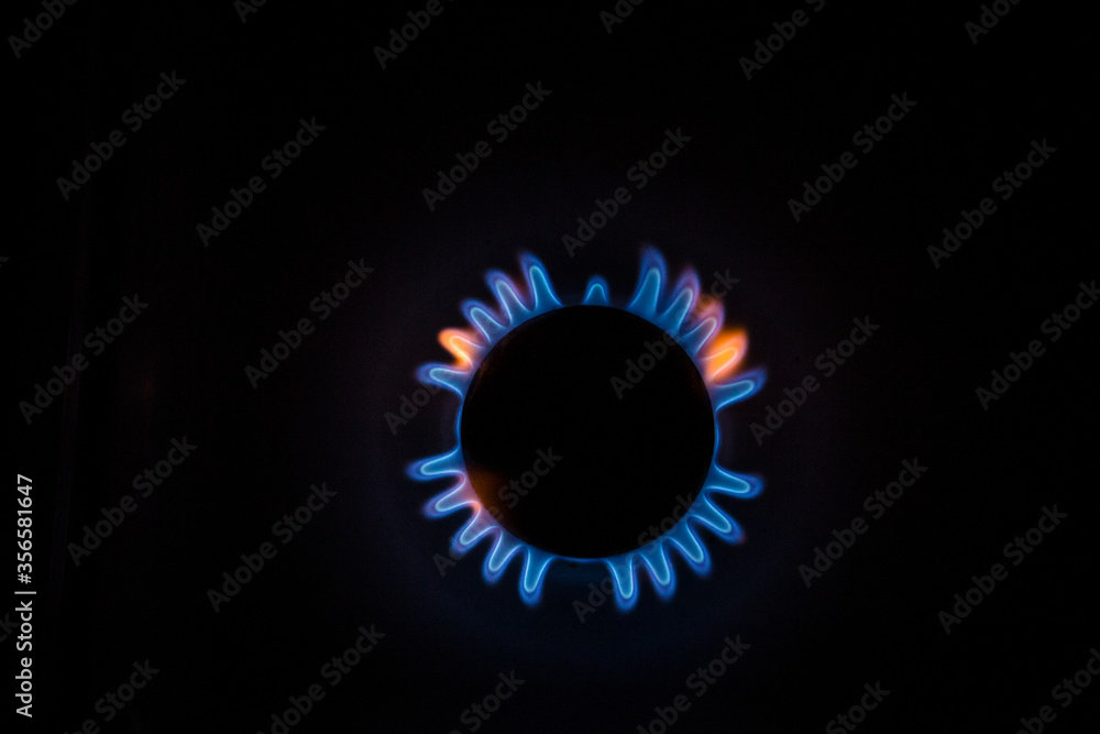 isolated close up shot of a blue and orange circular fire with small flames on the perimeter coming from a kitchen gas stove and forming a silhouette of an angel or a turtle on a black background isolated close up shot of a blue and orange circular fire with small flames on the perimeter coming from a kitchen gas stove and forming a silhouette of an angel or a turtle on a black background