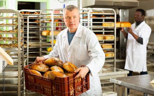 Bakery worker carrying box with loaves