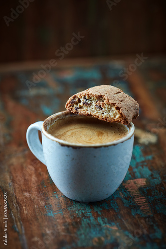 Cantuccini (Italian biscuits) with a cup of coffee on rustic wooden background. Close up. 