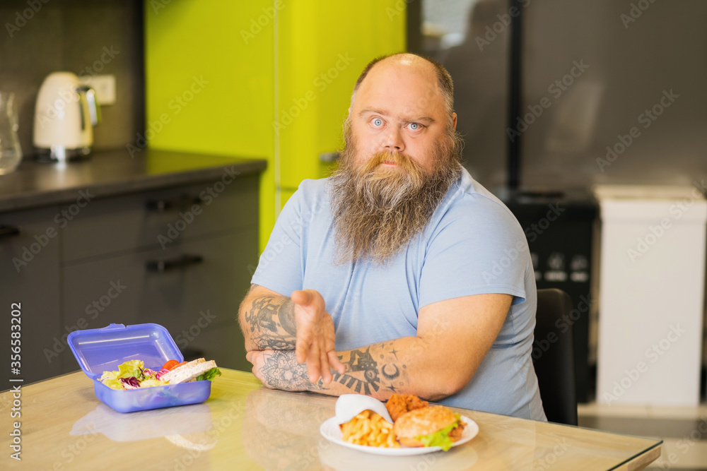 Bearded man sitting in kitchen at table with food