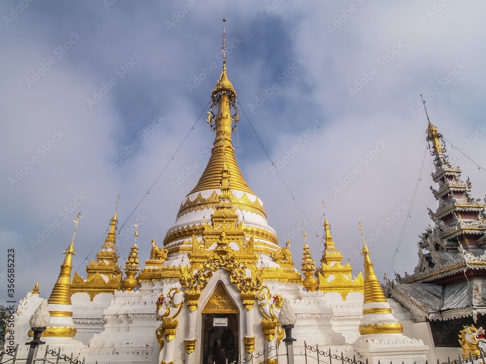 Naklejka premium view morning of Golden Pagoda around with soft mist and blue sky background, Wat Chong Kham, Mae Hong Son, northern of Thailand.