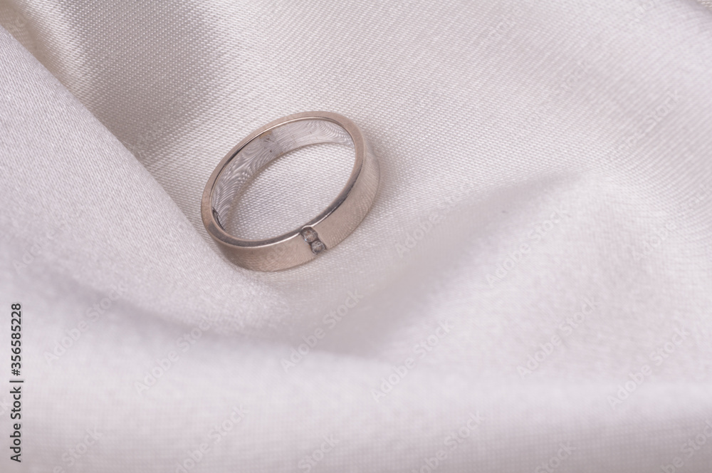 Wedding rings/ Engagement ring with diamonds isolated over white satin cloth Wedding rings/ Engagement ring with diamonds isolated over white satin cloth