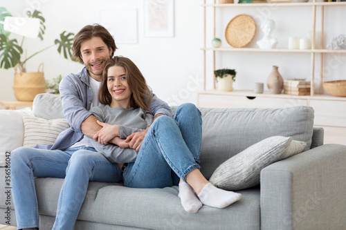 Young beautiful couple posing on couch at home