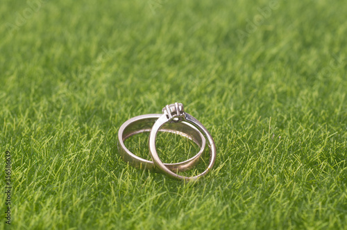 A pair of wedding/engagement ring isolated over green grass