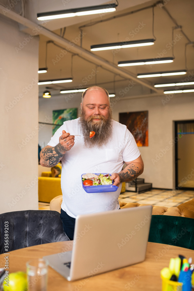 Bald bearded abdominous man in white tshirt having lunch Bald bearded abdominous man in white tshirt having lunch