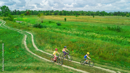 Family cycling on bikes outdoors aerial view from above, happy active mother with children have fun, family sport and fitness 