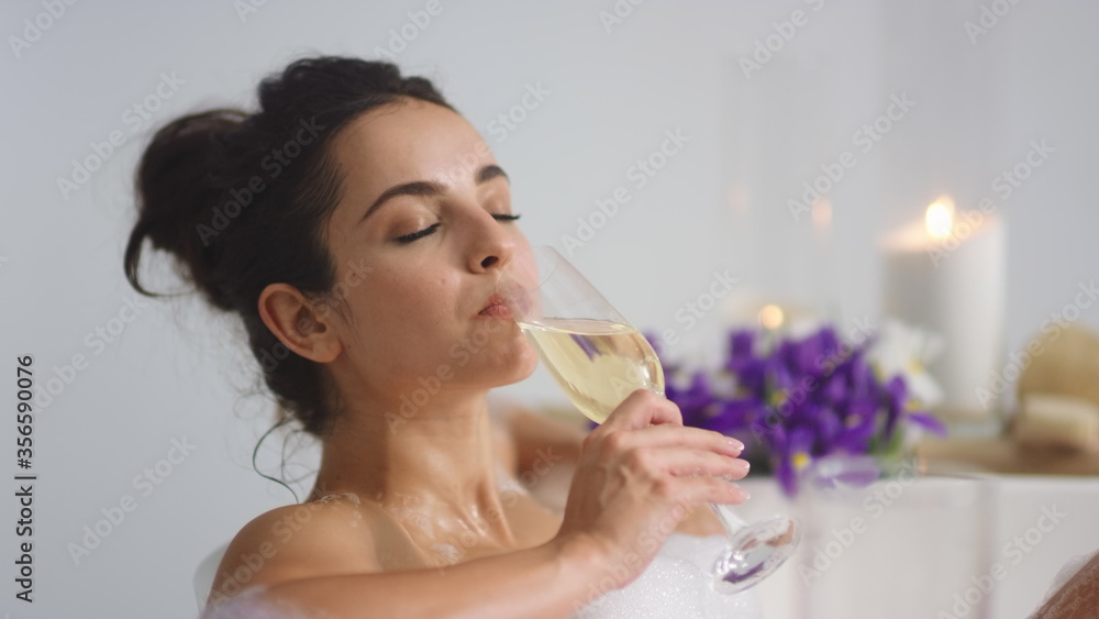 Relaxed woman drinking champagne in bath. Cute girl taking rest in bathtub Relaxed woman drinking champagne in bath. Cute girl taking rest in bathtub