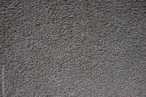 Gray doormat which is made from synthetic fibers.