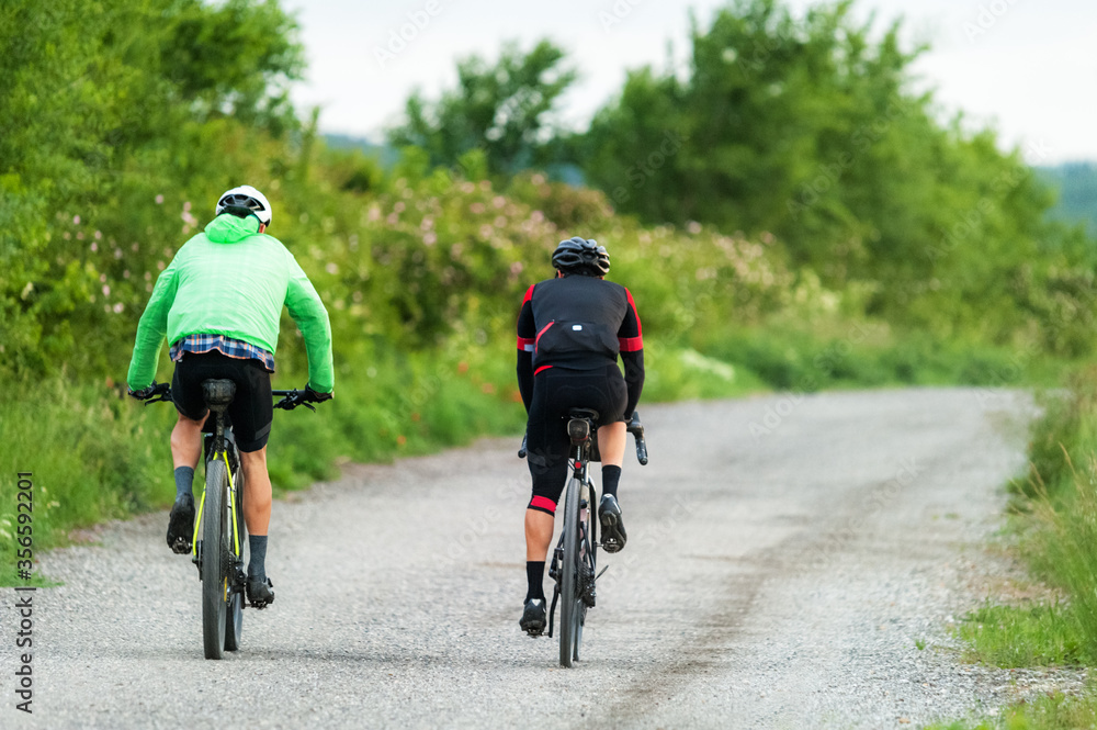 Fototapeta premium Two bikers with mountain bikes on a gravel road