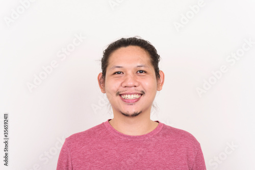 Portrait of happy Asian man smiling on white concrete wall photo