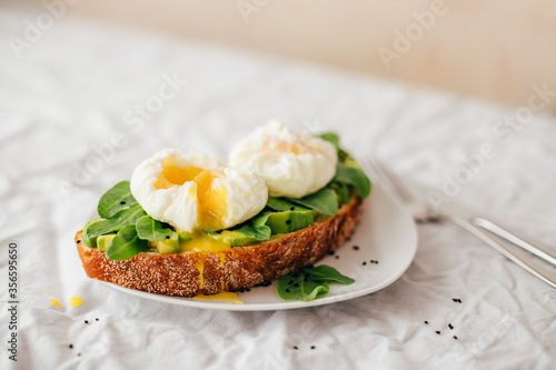 sandwich with avocado, arugula and poached egg sprinkled with nigella decorated with small gypsophila flowers
