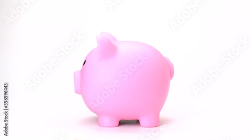 side view of hand putting coin into pig doll bank on white background. saving money on pink piggy bank isolate. - vdo 4k, 1080, fhd, full hd