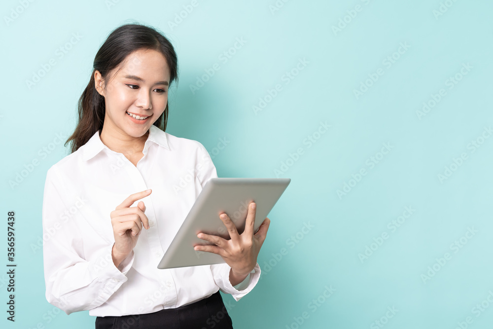 Portrait of young asian woman working online on tablet with happy on blue background with free copy space. Wireless connection technology concept. Portrait of young asian woman working online on tablet with happy on blue background with free copy space. Wireless connection technology concept.