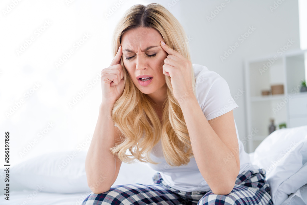 Photo of displeased blond house wife lady sitting bed white sheets quarantine time stay home suffer morning terrible migraine hold touch fingers temples wear pajama room indoors Photo of displeased blond house wife lady sitting bed white sheets quarantine time stay home suffer morning terrible migraine hold touch fingers temples wear pajama room indoors