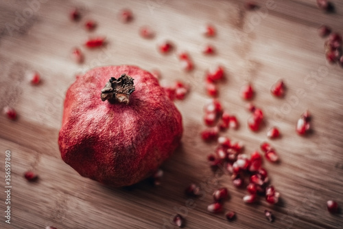 pomegranate with sprinkled grains on a wooden background