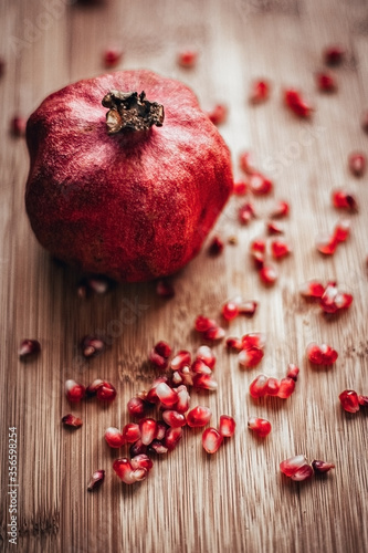 pomegranate with sprinkled grains on a wooden background