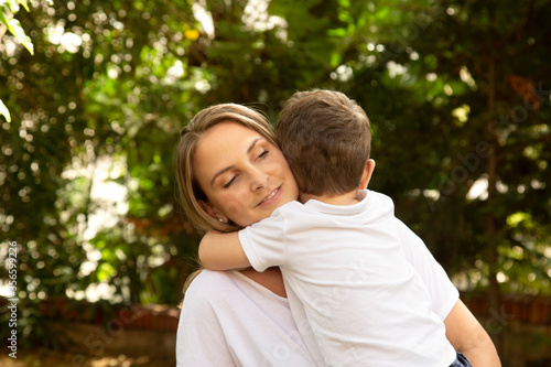 bambino abbraccia teneramente la madre e la riempie di baci nel giardino di casa