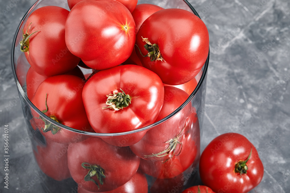 Fresh large tomatoes on a gray background. Whole and sliced tomatoes shot closeup with meta for text. Art concept tomatoes in the glass. Fresh large tomatoes on a gray background. Whole and sliced tomatoes shot closeup with meta for text. Art concept tomatoes in the glass.