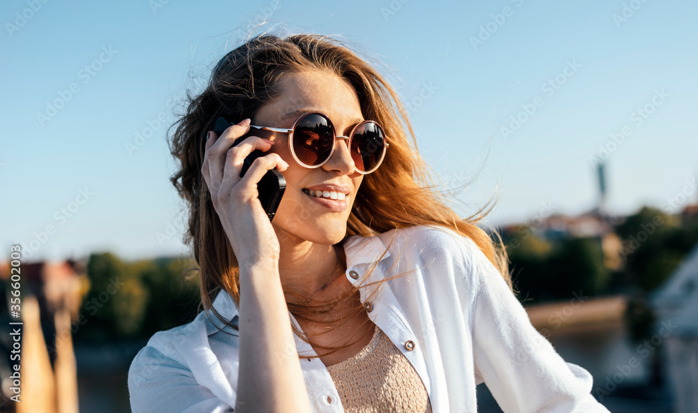 Young blonde tourist is talking on phone being outdoors Young blonde tourist is talking on phone being outdoors