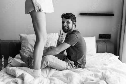 Young man and woman fooling around and having fun on the bed.
