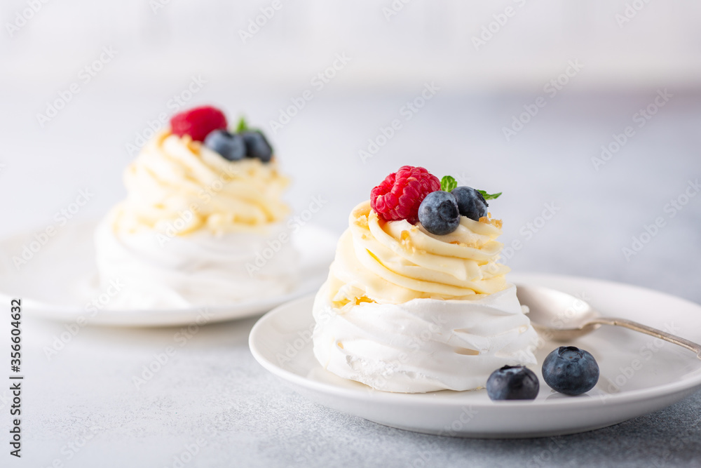 Delicious Pavlova cake with whipped cream and fresh berries on white plate. Stone background. Selective focus Delicious Pavlova cake with whipped cream and fresh berries on white plate. Stone background. Selective focus